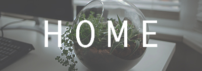 Clear bowl on desk with plants with white letters saying home