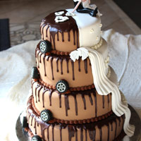 A four-layer cake with one side looking like melting chocolate and tires, while the other looks like a traditional wedding cake. Click here for a larger picture.