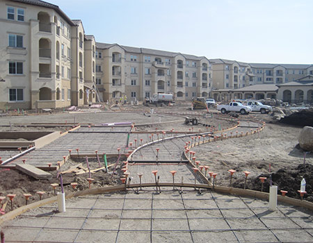 This is an image of our flatwork ready to be poured. There are form boards, rebar and other reinforcing in place to make the concrete structurally sound. The sidewalk is in the middle of an appartment complex.