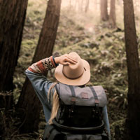 A woman looks up into the trees while hiking.