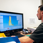 Engineer sitting infront of computer designing customers part.