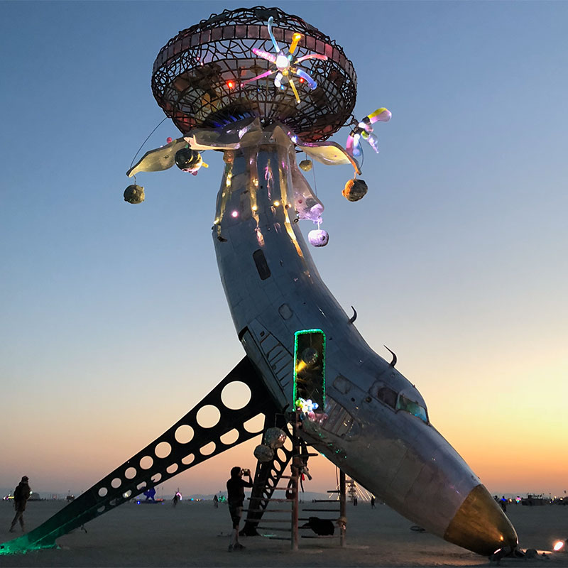 A sculpture made from an airplane made to look like a banana with the desert sunset in the background