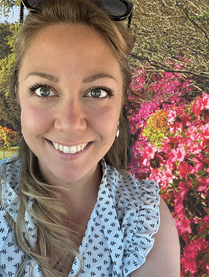 A selfie taken in front of a garden