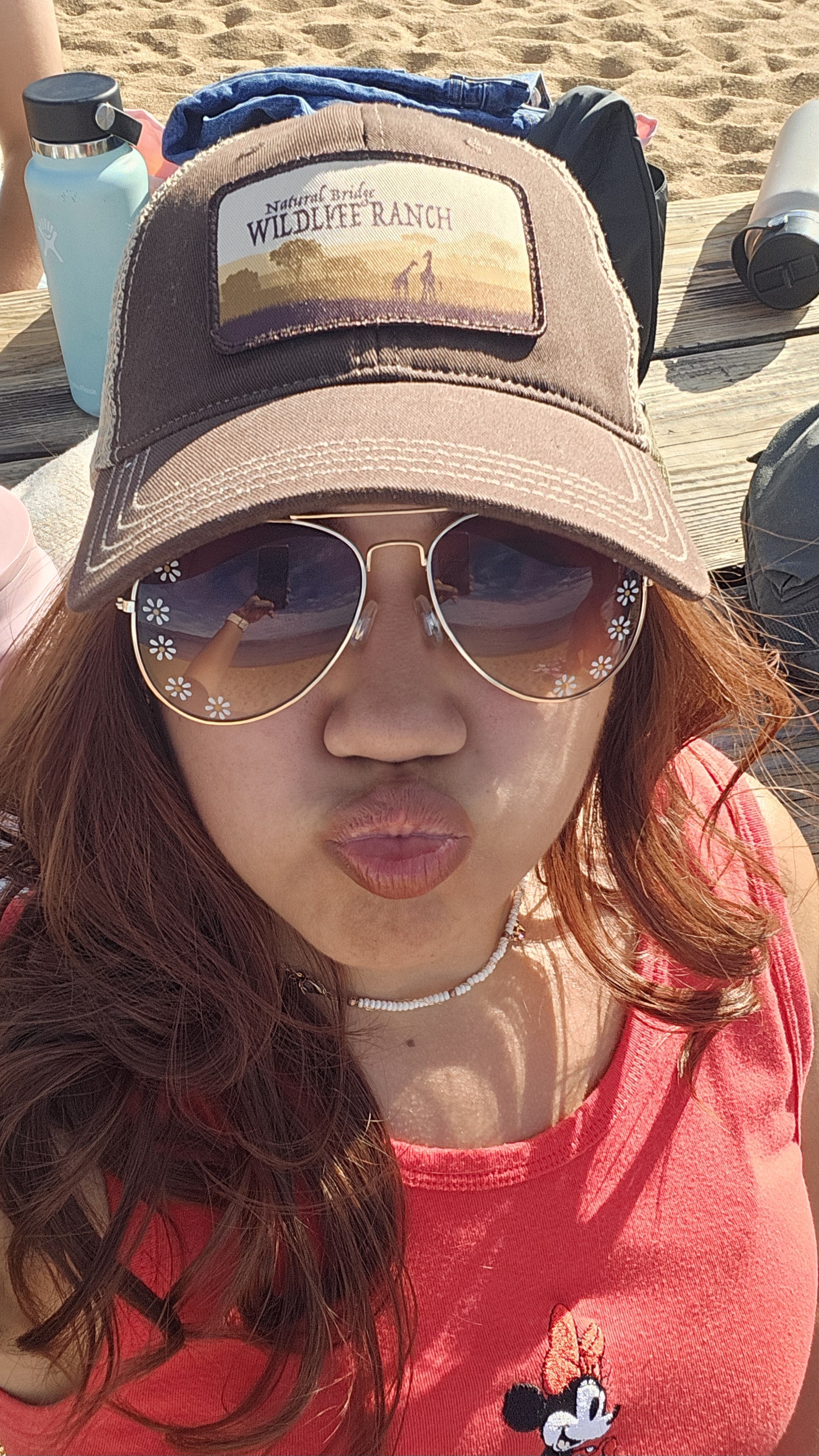 A woman wearing a baseball cap and sunglass whiling smooching her lips.