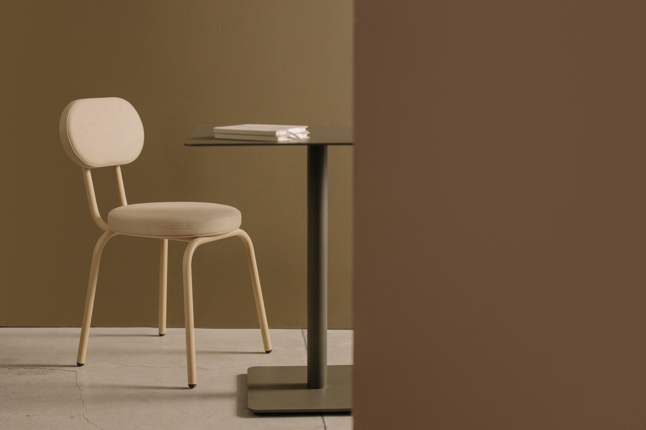 A chair is situated next to a table with a journal on top of it.