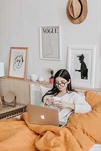 Woman drinking tea while working on her laptop