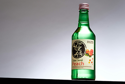Bottle of peach-flavored soju on a minimal background