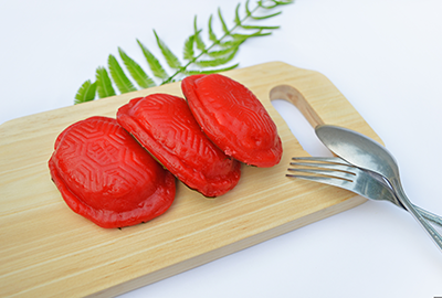 Red glutinous rice cakes with fork on bamboo tray