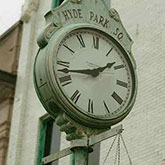 Upper third of a light green street clock telling time.