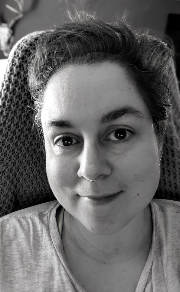 Talie's selfie. The photo is black and white and they are subtly smiling at the camera.