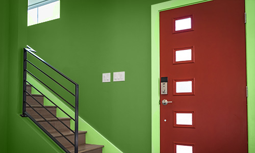 Doorway with red door, green walls, and light green trim