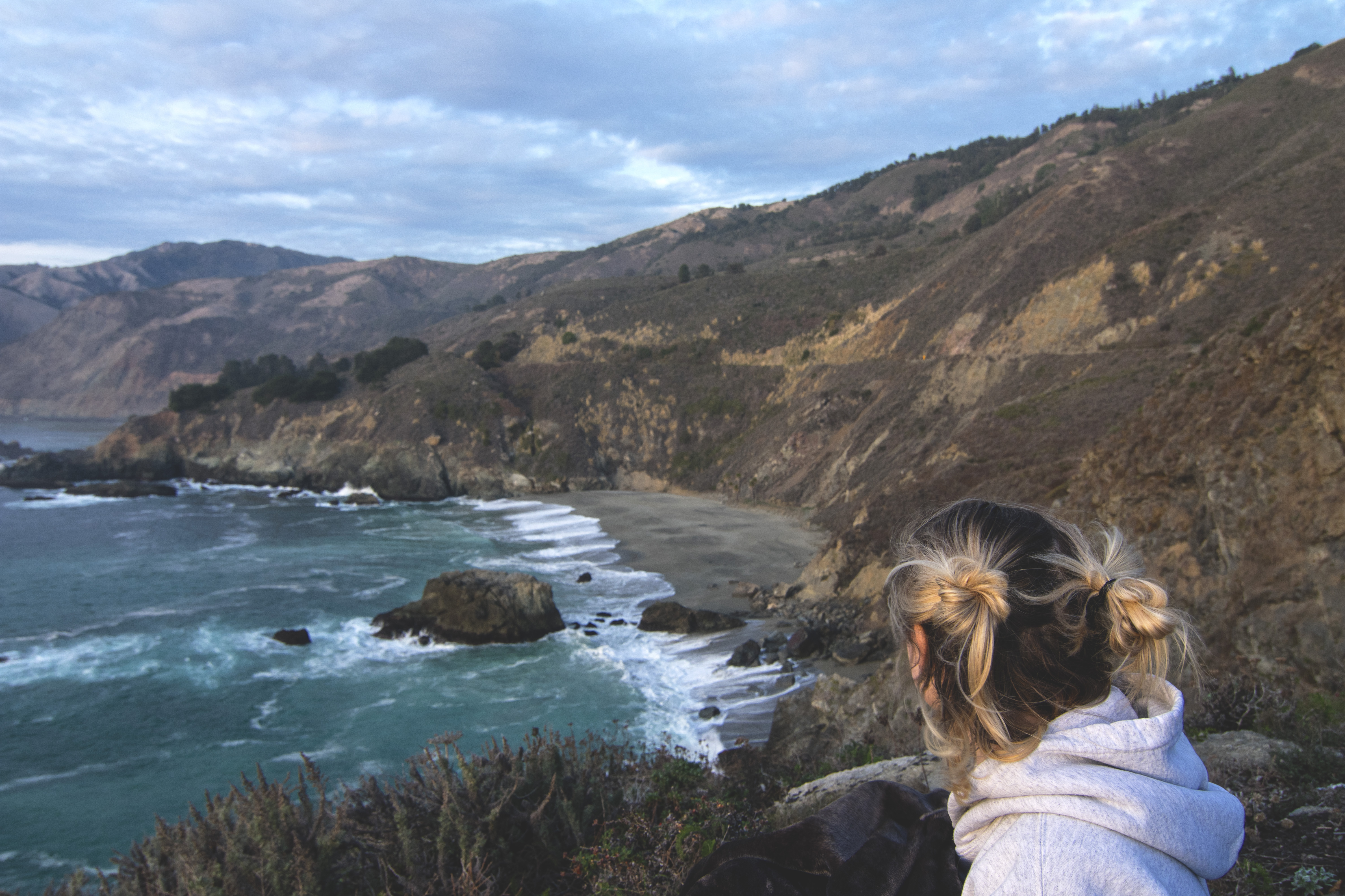Blonde woman looking over the California coastline