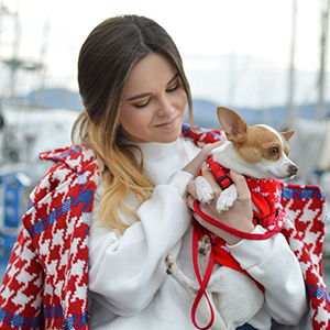 woman looking lovingly at a small dog she is holding in her arms