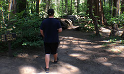 Person walking donw path with sign to the left pointing the way